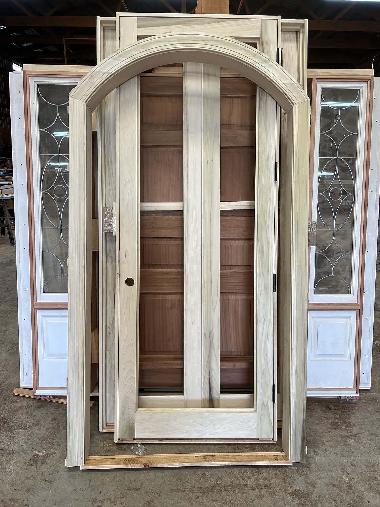 Custom arched door frame paired with a leaded-glass panel door, unfinished in the workshop