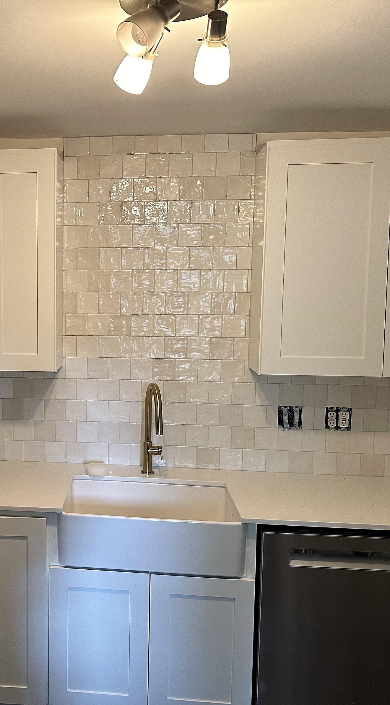 Finished vanity-style cabinetry with a farmhouse sink, gooseneck faucet, and tile backsplash