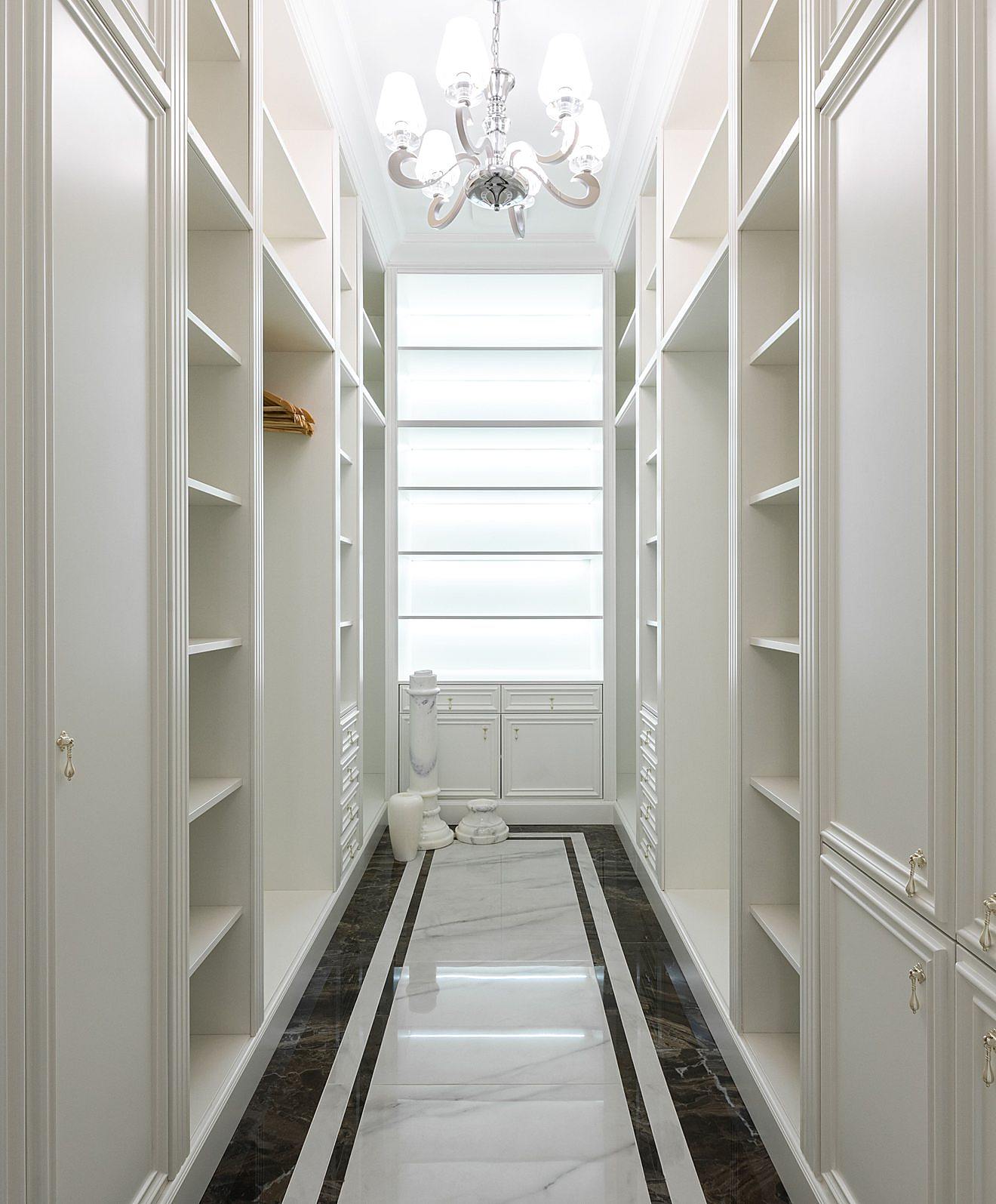 Luxury walk-in closet with built-in cabinetry, open shelving, a chandelier, and a marble floor inlay