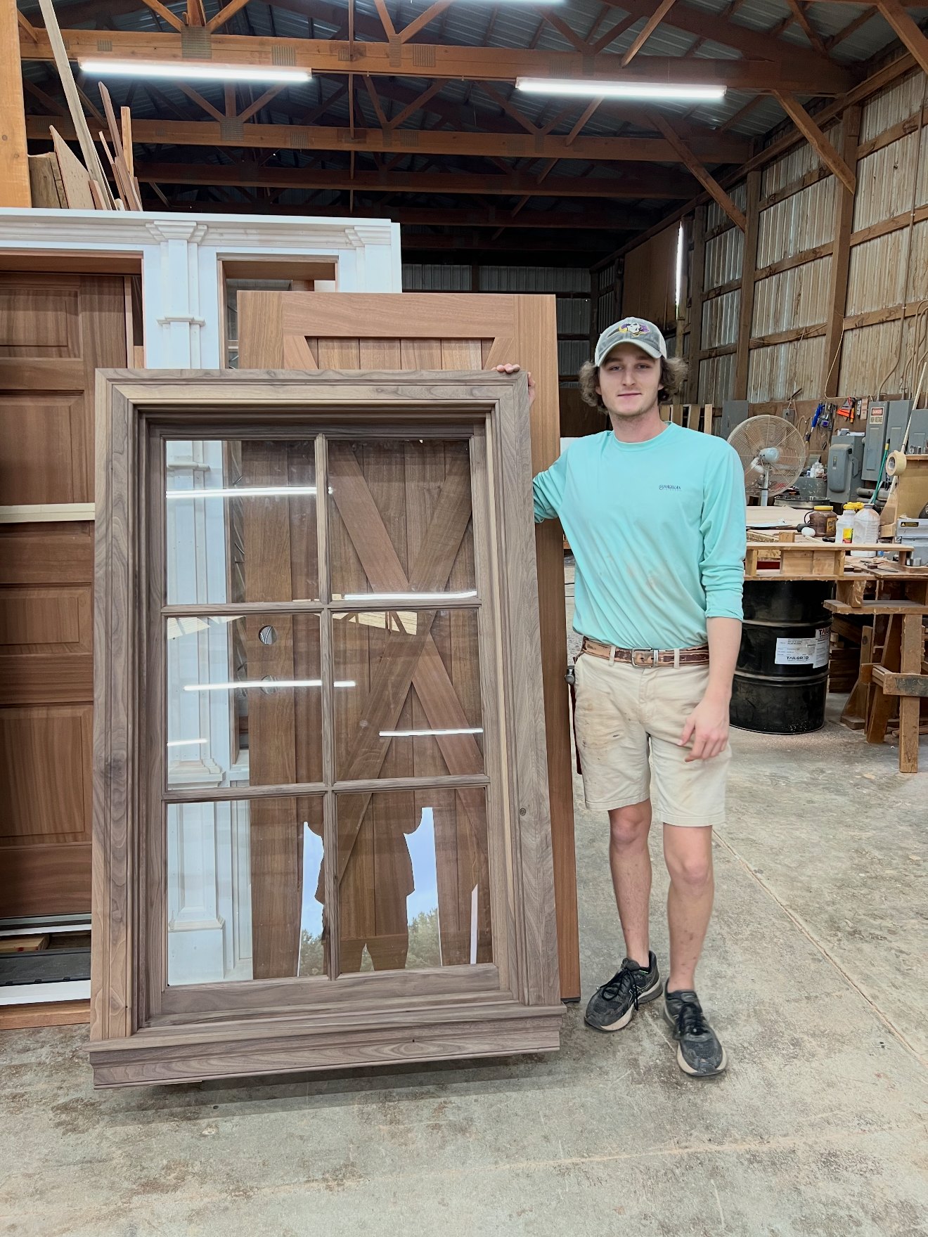 Trident Custom Cabinets craftsman holding a handcrafted solid walnut window sash and frame in the workshop