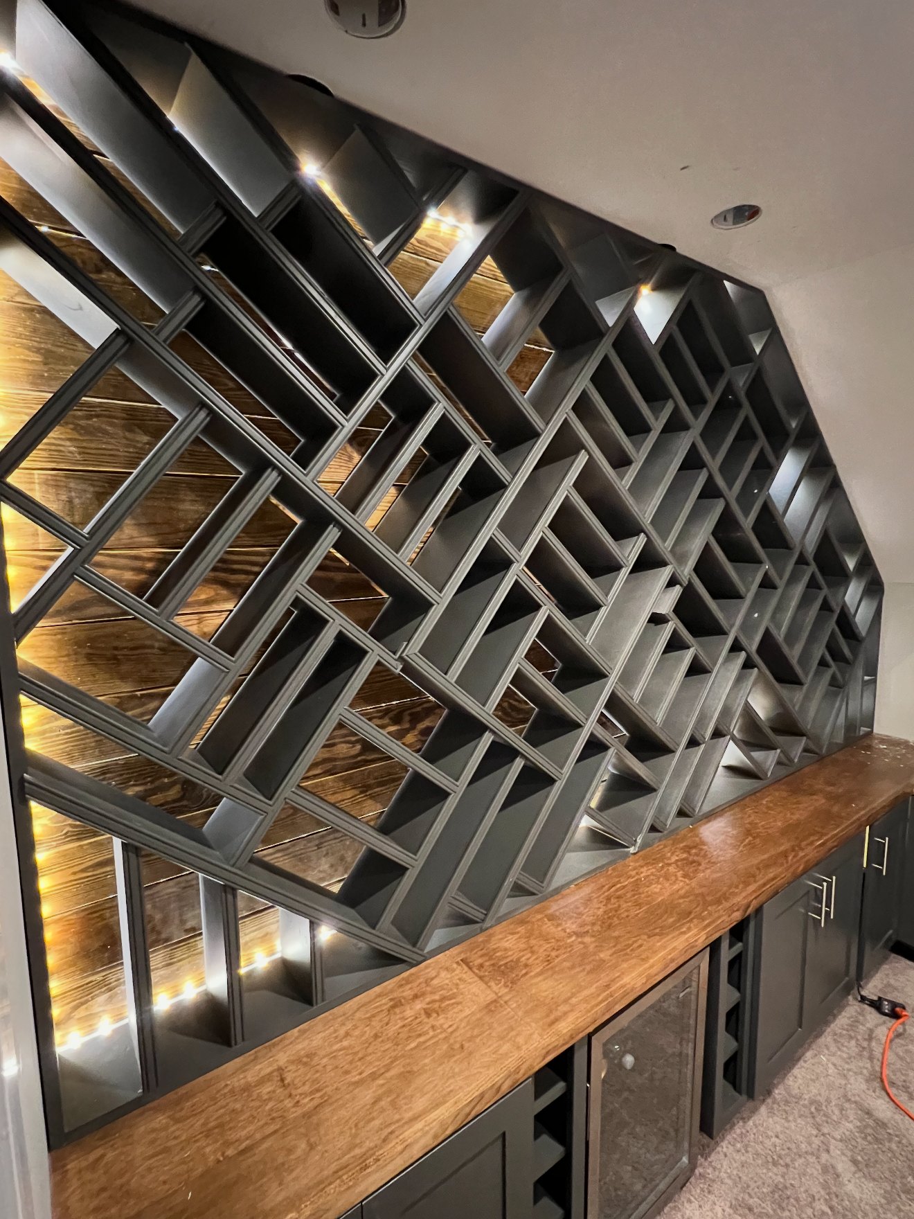 Custom geometric built-in display and wine wall with integrated LED lighting and live-edge wood counter