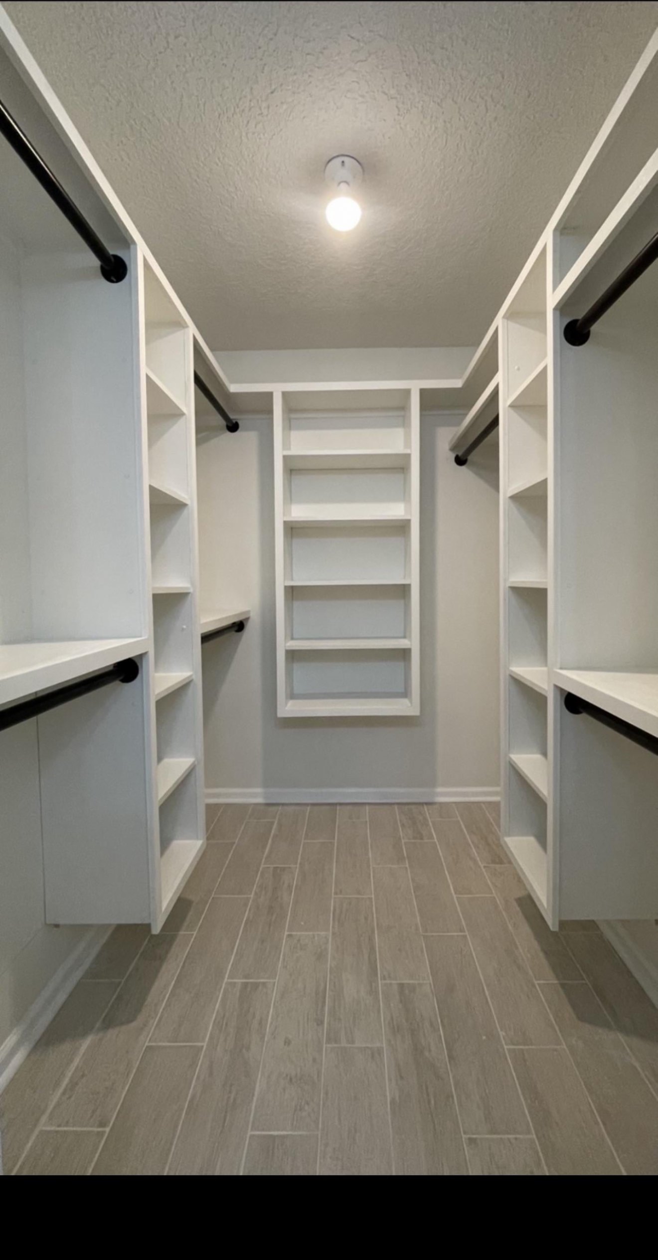Custom walk-in closet with built-in shelving, hanging rods, and center storage tower