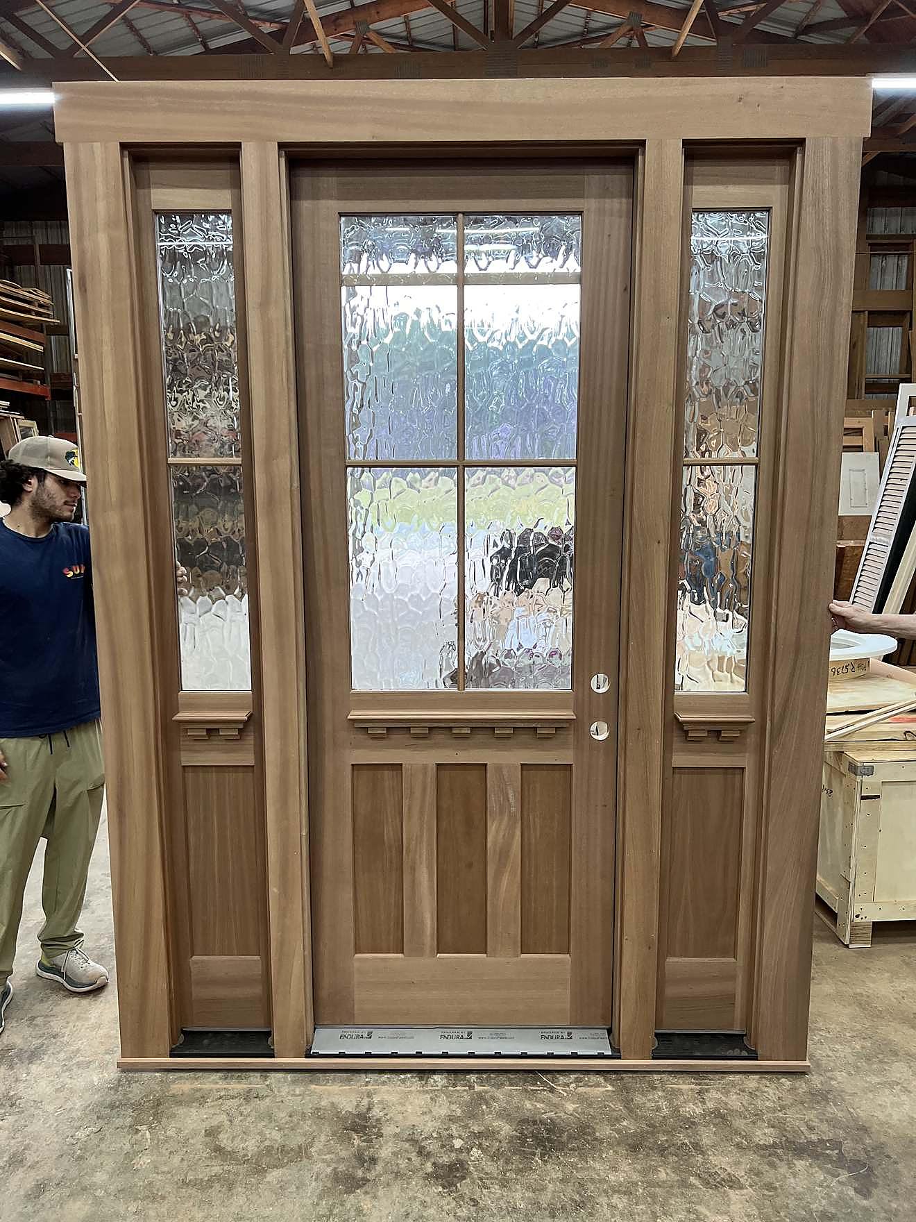 Custom wood door with glass sidelights and privacy glass, staged in the workshop