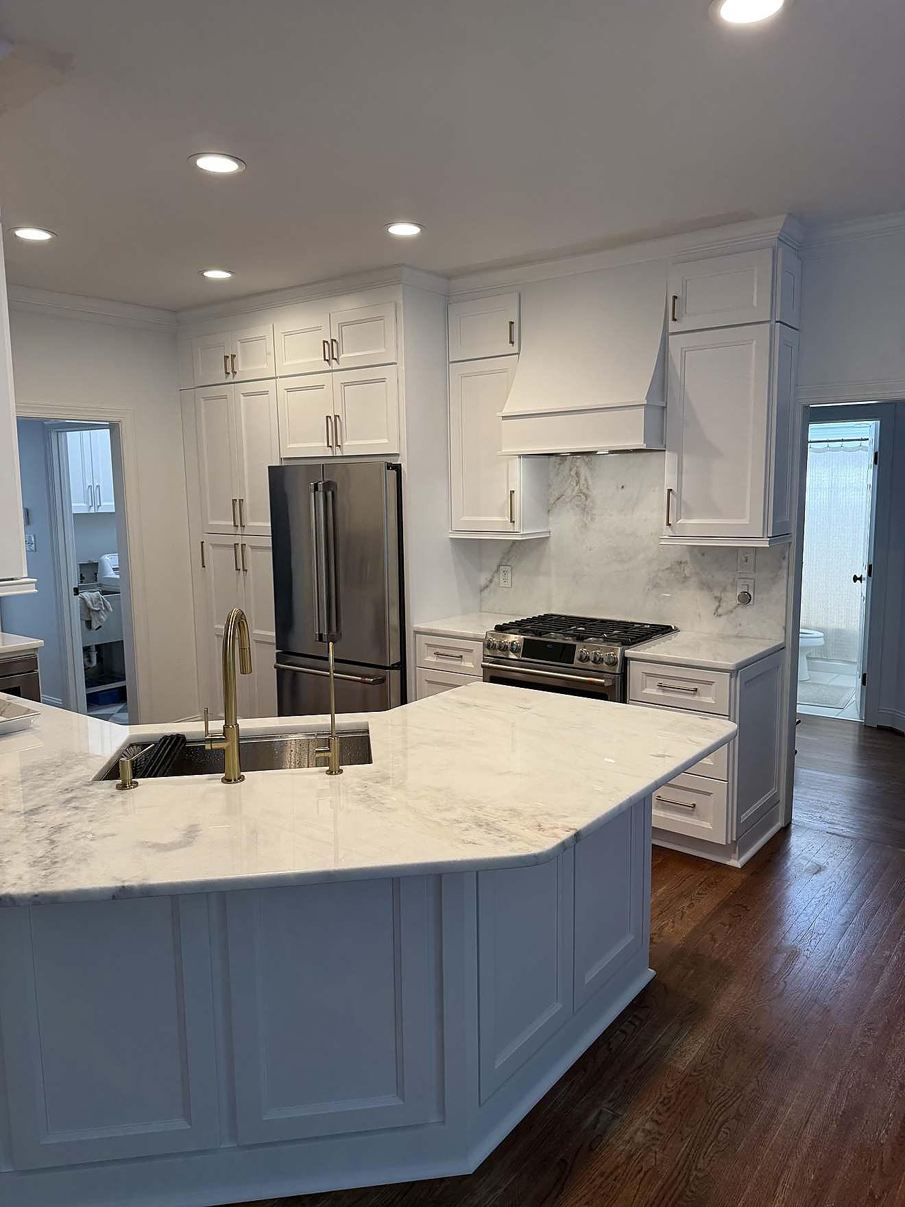 Finished kitchen remodel with white cabinetry, a blue island, and marble-look countertops