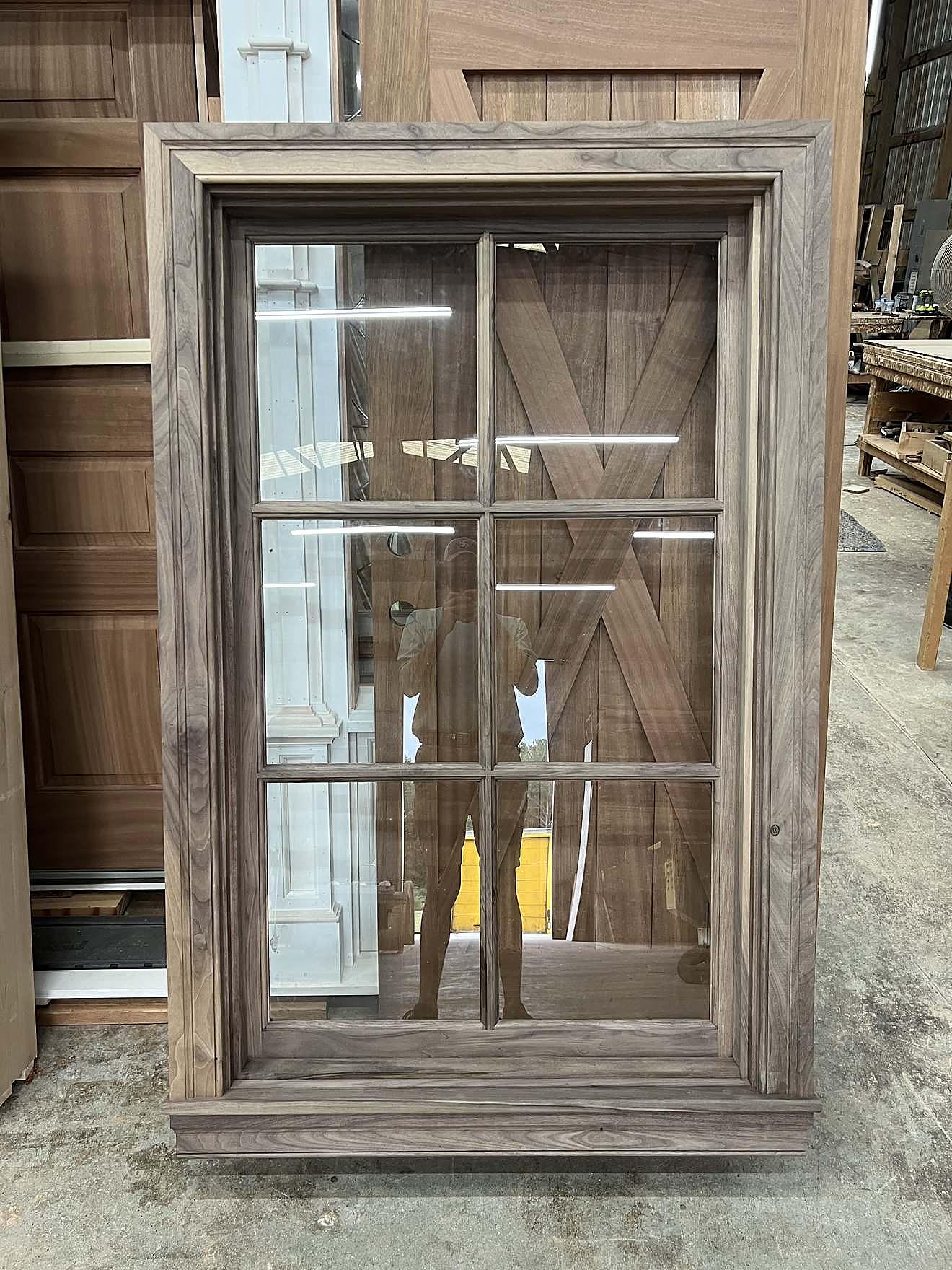 Custom walnut-finished window with a barn-style X brace panel behind the glass